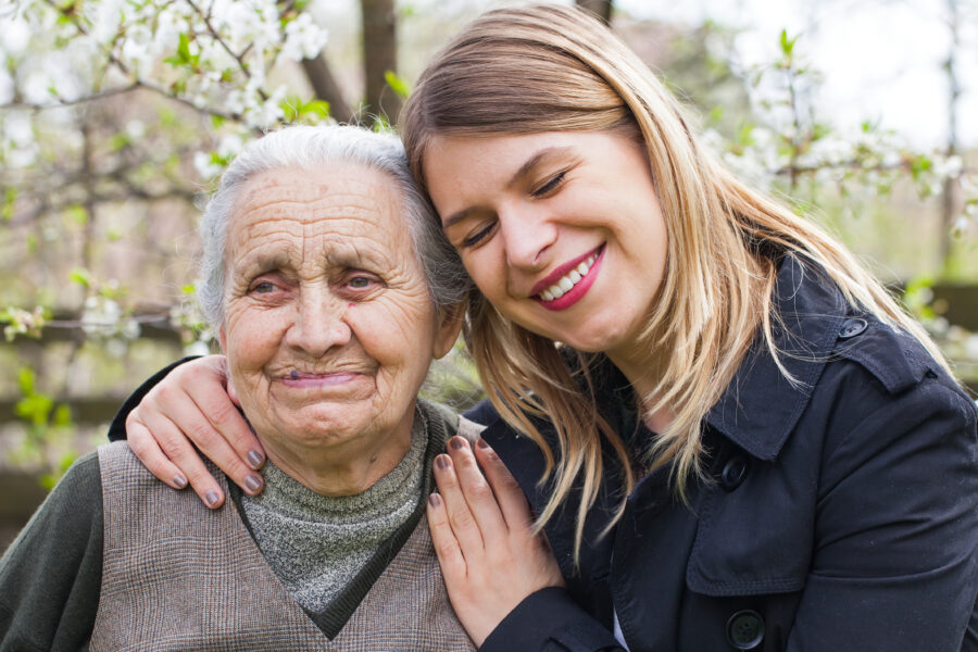 Woman hugging elderly woman suffering from dementia