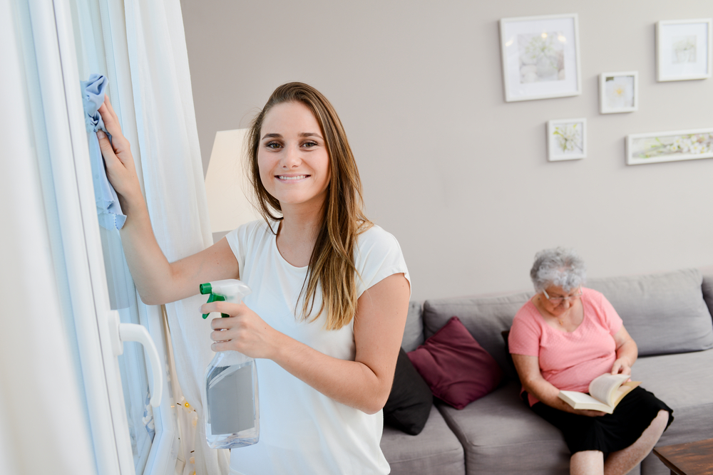 Woman cleans house for senior woman providing personal home care.