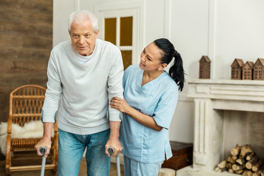 Caregiver helping man walk in his home